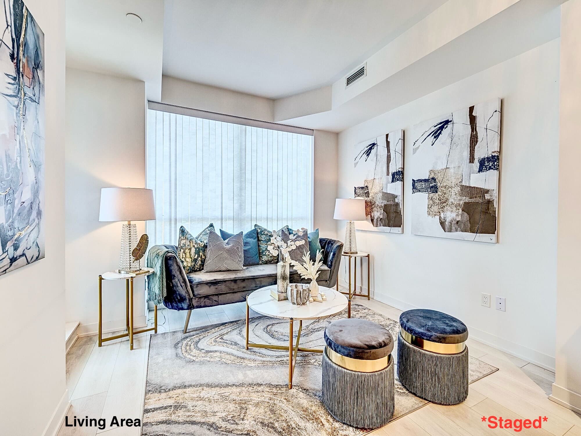 Contemporary living room with a blue velvet sofa, marble coffee table, and abstract paintings.
