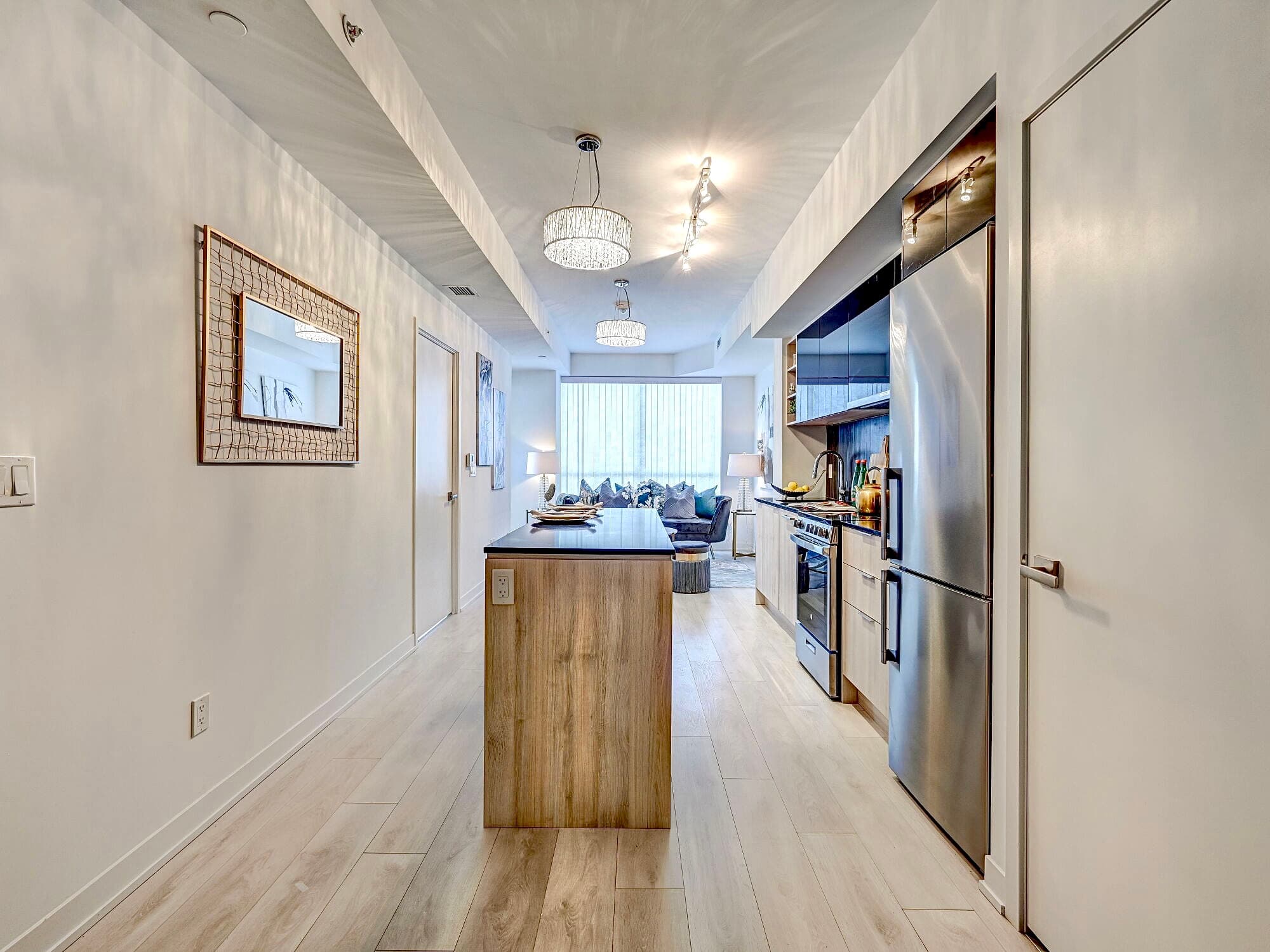 Modern kitchen featuring a wood island, stainless steel appliances, and a bright living area.