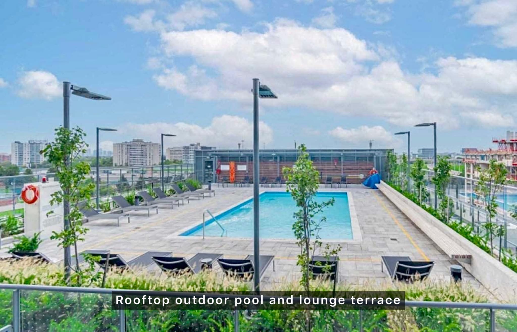 Rooftop outdoor swimming pool and lounge terrace with sun loungers overlooking a city skyline.