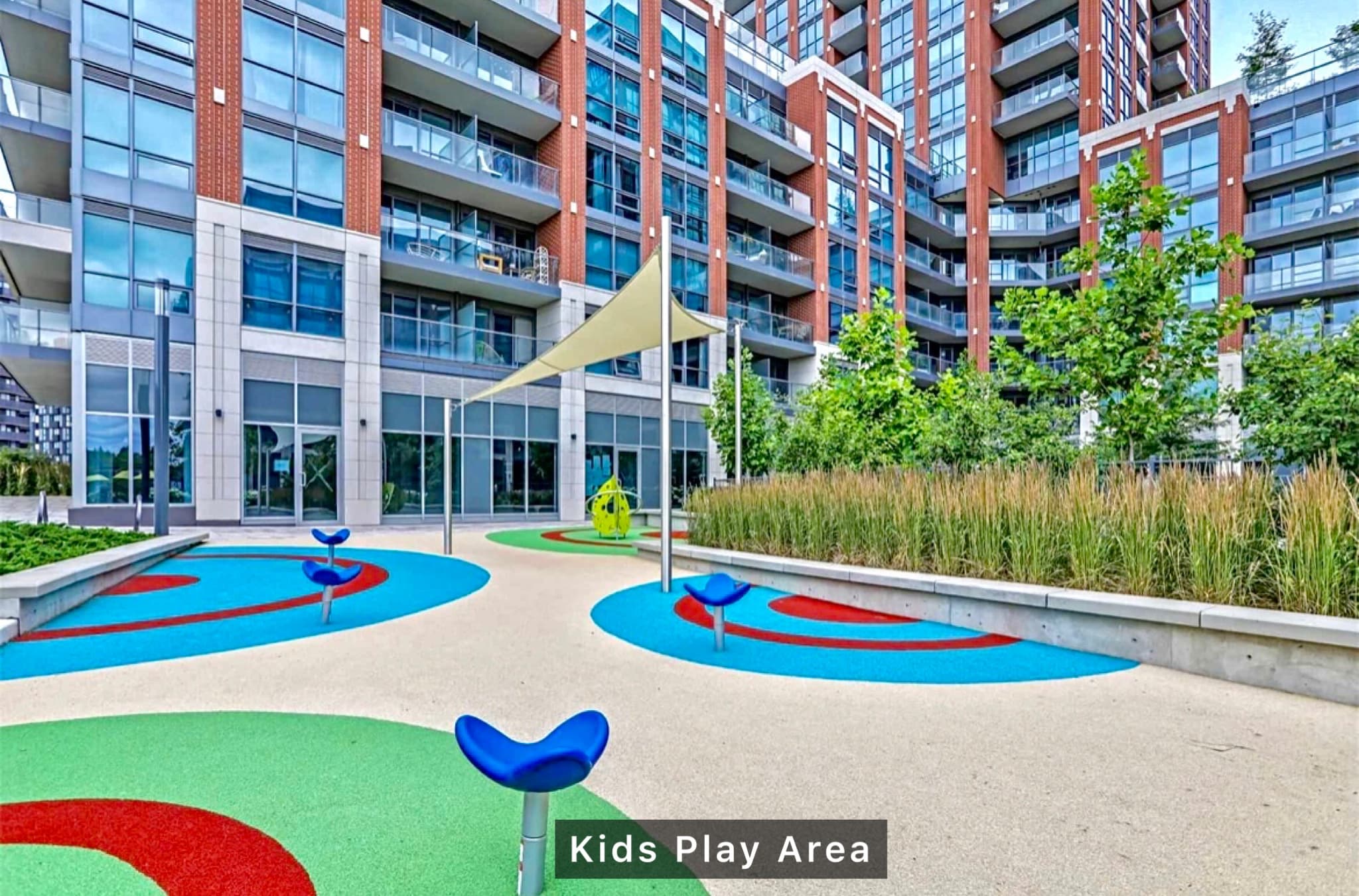 Modern playground with colorful circular patterns and blue spring riders outside a high-rise building.