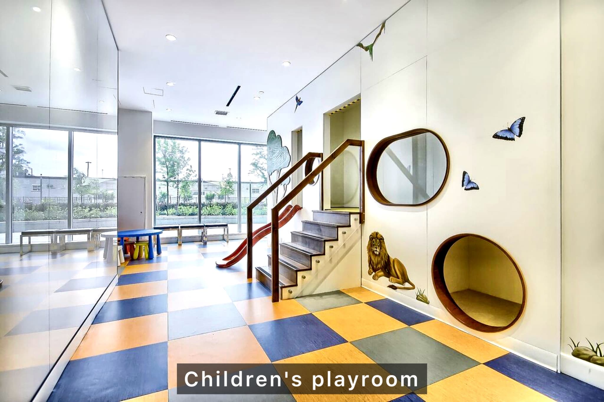 Bright children's playroom featuring checkered floors, a small slide, stairs, and animal-themed wall decals.