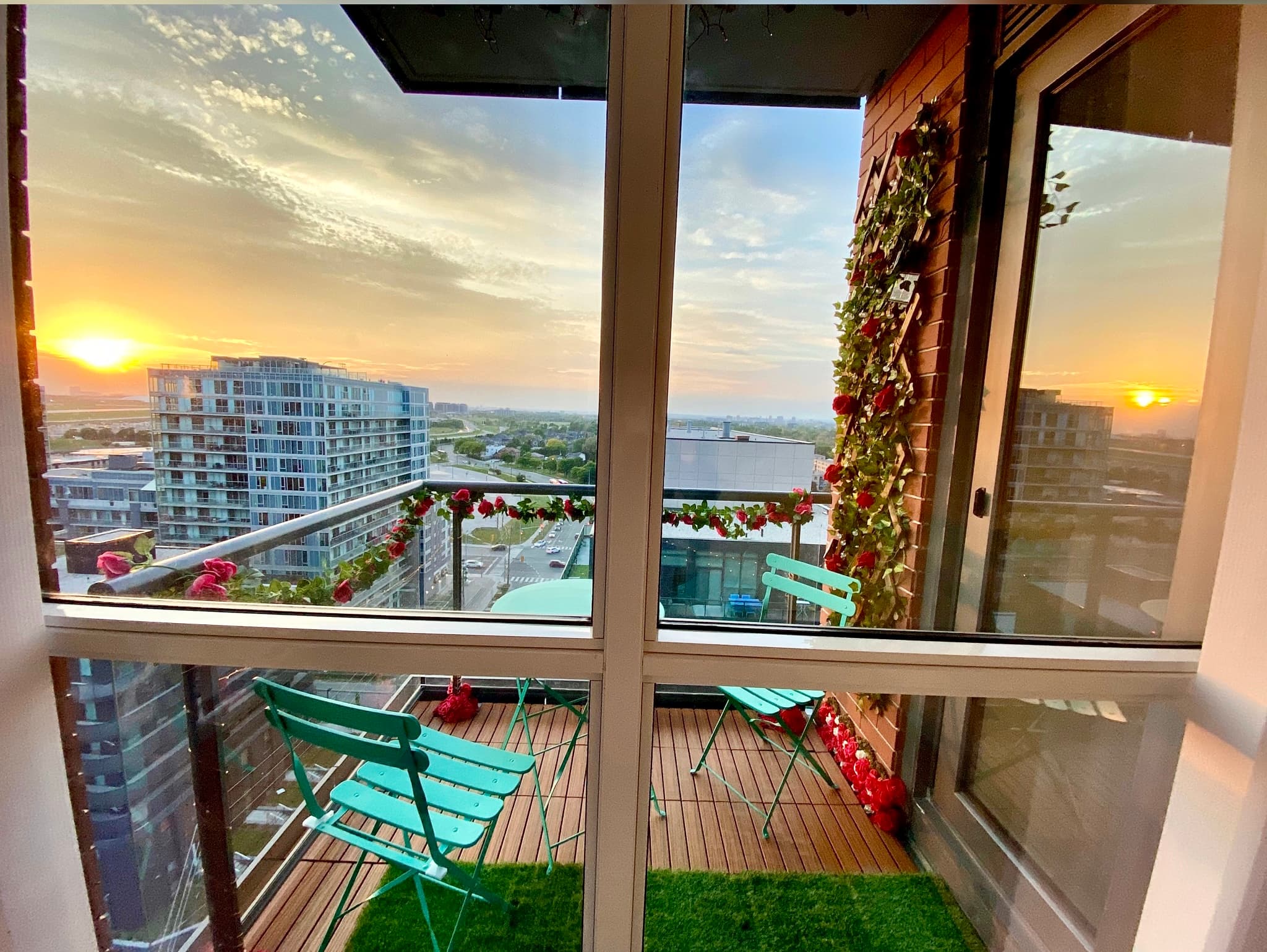 Teal chairs and red rose garlands on a balcony overlooking a golden city sunset.
